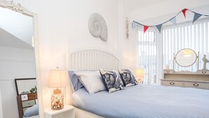 Une chambre à coucher comprenant un lit, des tables de chevet, une commode, un miroir et un élément décoratif mural.