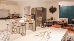 Une cuisine moderne avec des meubles blancs, un réfrigérateur en acier inoxydable et un coin repas comprenant une table et des chaises blanches.