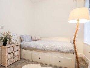 Un dormitorio con una cama, mesitas de noche, una lámpara y una planta en maceta.