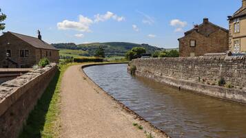 A narrow waterway flanked by stone walls and buildings, with a clear sky and distant hills.