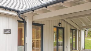 A covered entrance to Mountain Hare Apartment with a sliding glass door and a sign above it. - Mountain Hare Apartment (Kingussie)
