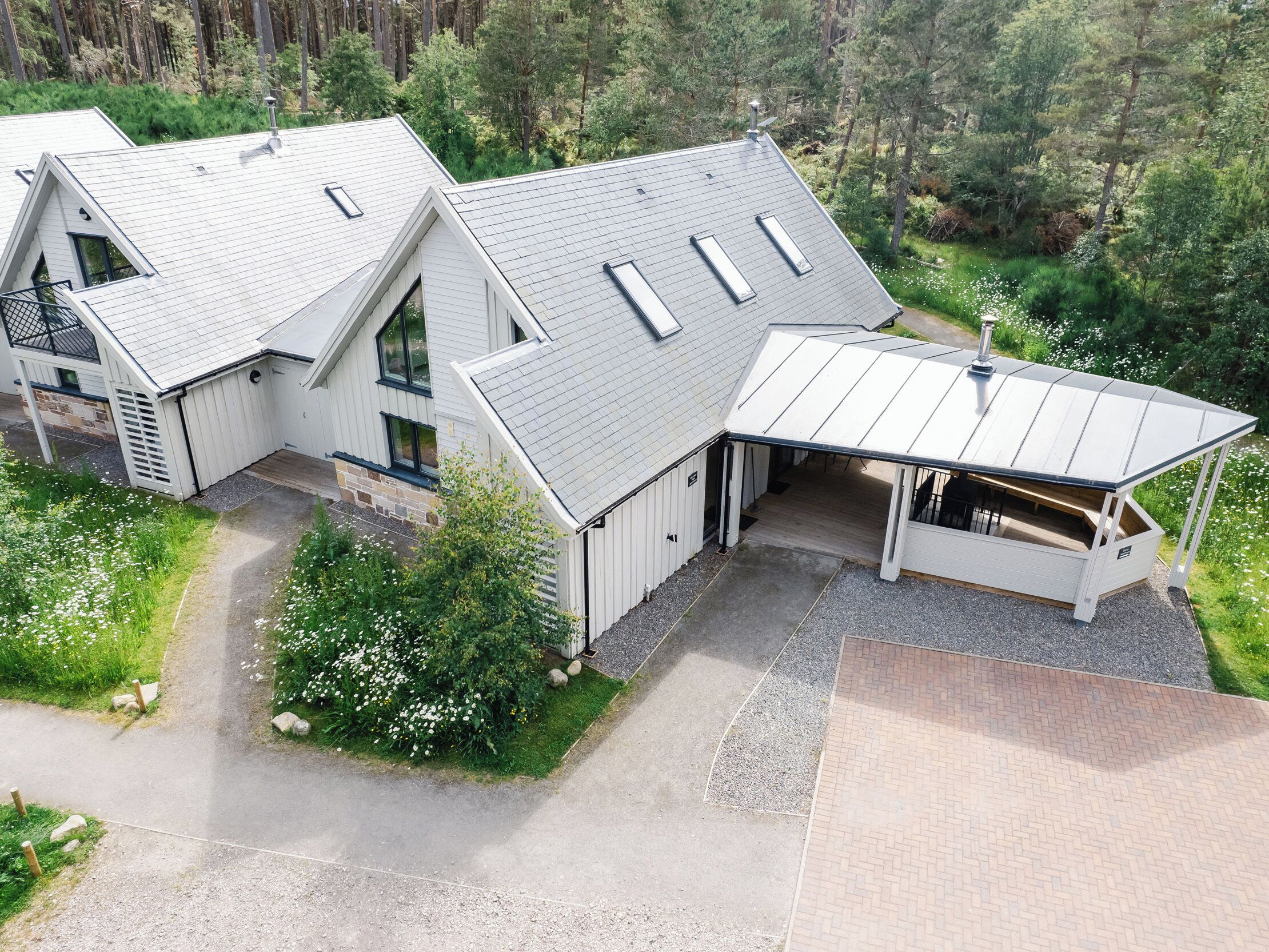 A modern house with a sloped roof, multiple skylights, and a covered porch.
