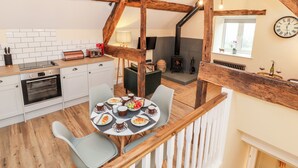 Una cocina moderna con armarios blancos, horno empotrado y un comedor con mesa redonda dispuesta para una comida.