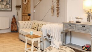 A cozy living room with a tufted sofa, a wooden coffee table, and a decorative console table with a lamp.