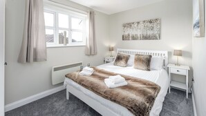 Un dormitorio con una cama blanca, un plaid de piel sintética y un cuadro en la pared.