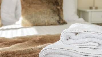 A neatly made bed with white linens and a brown blanket.