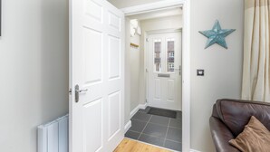 Un pasillo con una puerta blanca, un sofá de cuero marrón y una decoración con forma de estrella en la pared.