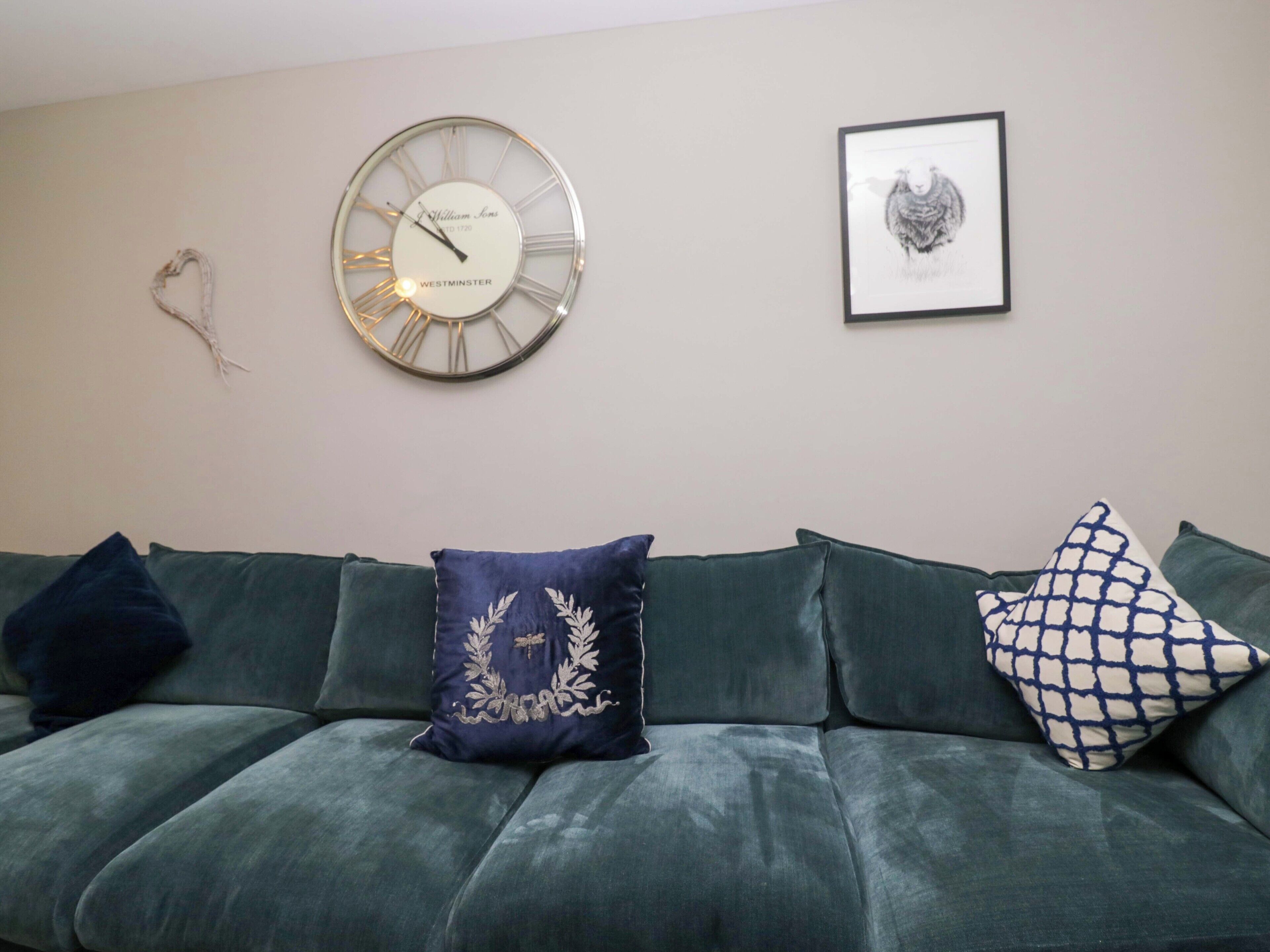 A living room with a green sofa, a wall clock, and a framed picture.