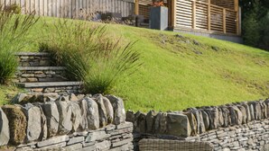 A stone retaining wall with a wooden pergola and a stone staircase. - Bishop Fell (Ulverston)