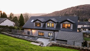 A modern two-story house with a sloped roof, a stone wall, and a grassy yard. - Bishop Fell (Ulverston)