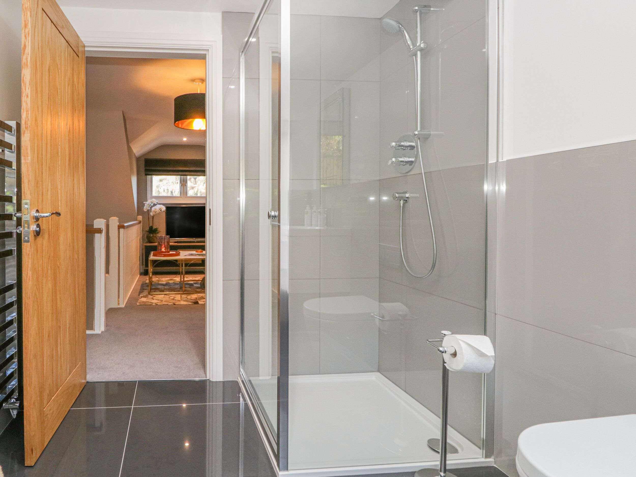 A modern bathroom with a glass shower enclosure, a toilet, and a sink.
