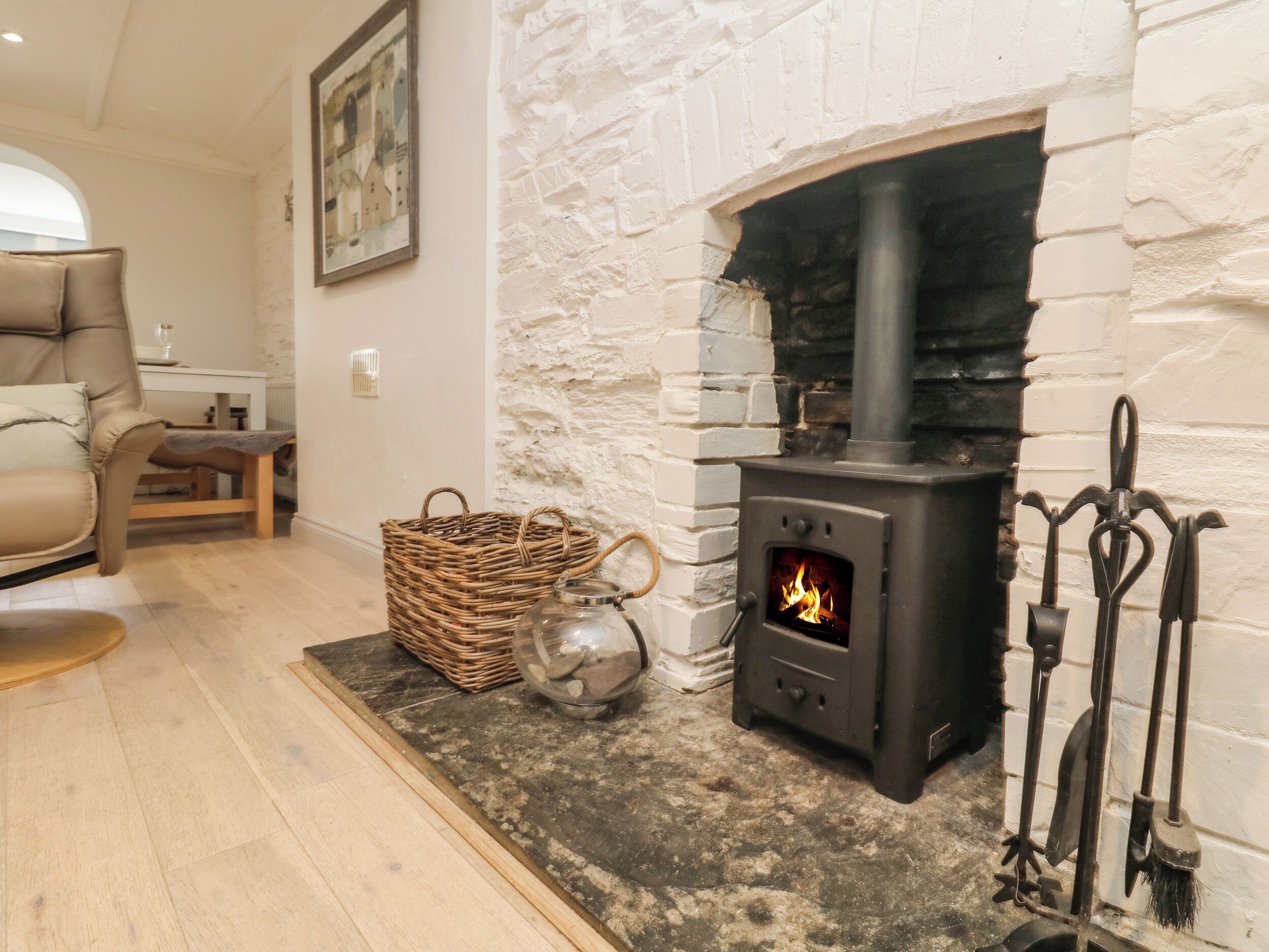 A cozy living room with a stone fireplace, a wicker basket, and a glass jar on the floor.