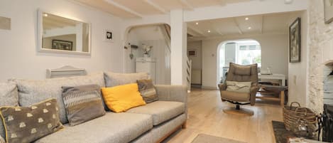 A spacious living room with a grey sofa, a wooden coffee table, and a fireplace.