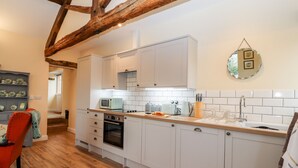 A kitchen with white cabinets, a wooden ceiling, and a tiled backsplash. - Cut Moch, Plas Moelfre Hall Barns (Oswestry)