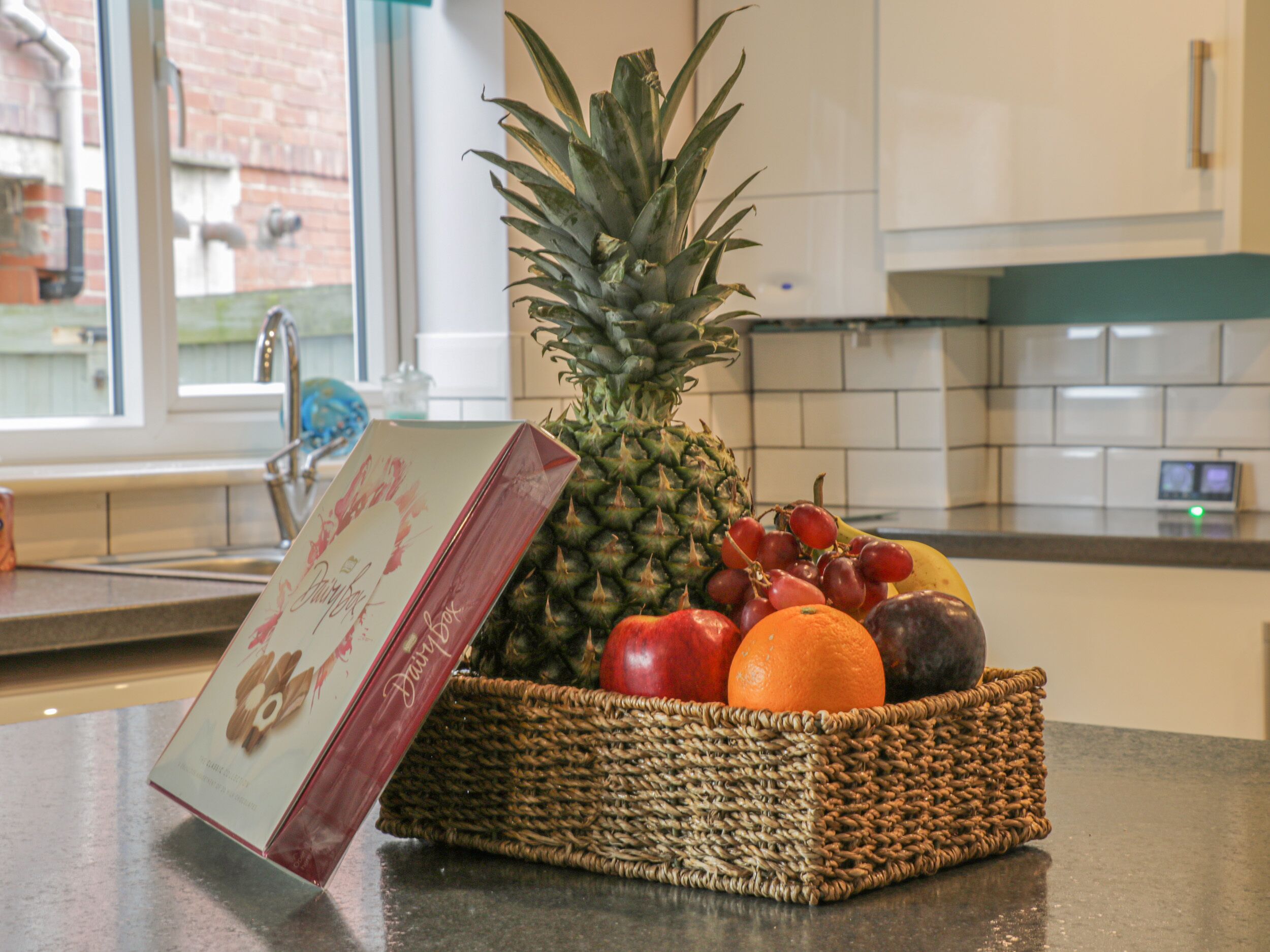 A kitchen counter with a woven basket containing fruits and a card.