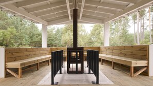 Un espacio al aire libre techado con bancos de madera y una mesa central.