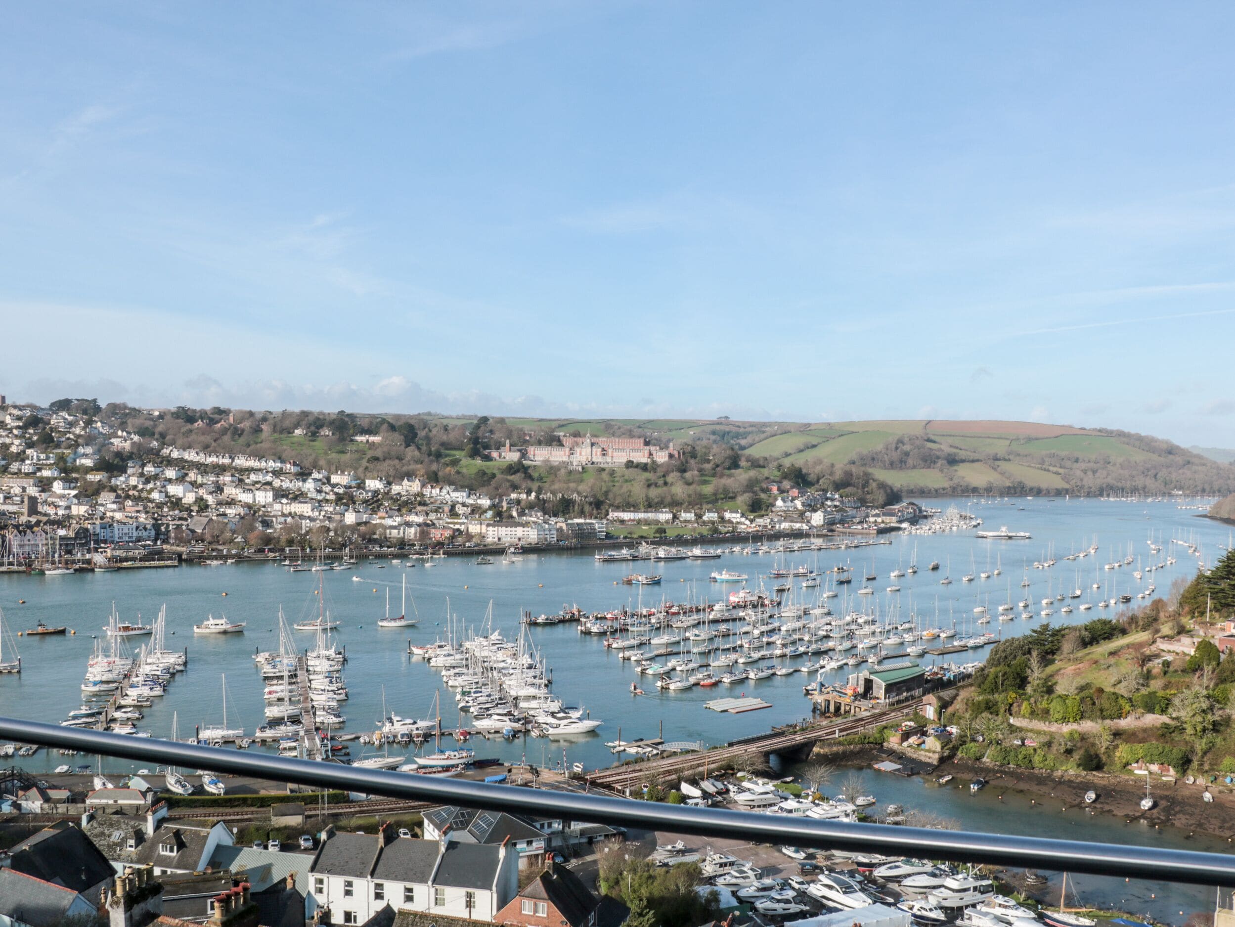 A marina filled with boats, a town in the background, and a bridge connecting the two.