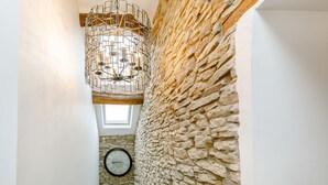 A stone wall with a clock and a geometric light fixture. - Carr House Farm (Glossop)