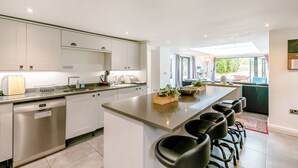 A modern kitchen with a central island, stainless steel appliances, and a seating area with bar stools. - Carr House Farm (Glossop)