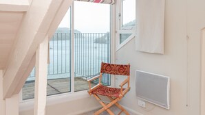 Una habitación con vista al mar, una silla plegable, un radiador y una alfombra pequeña.