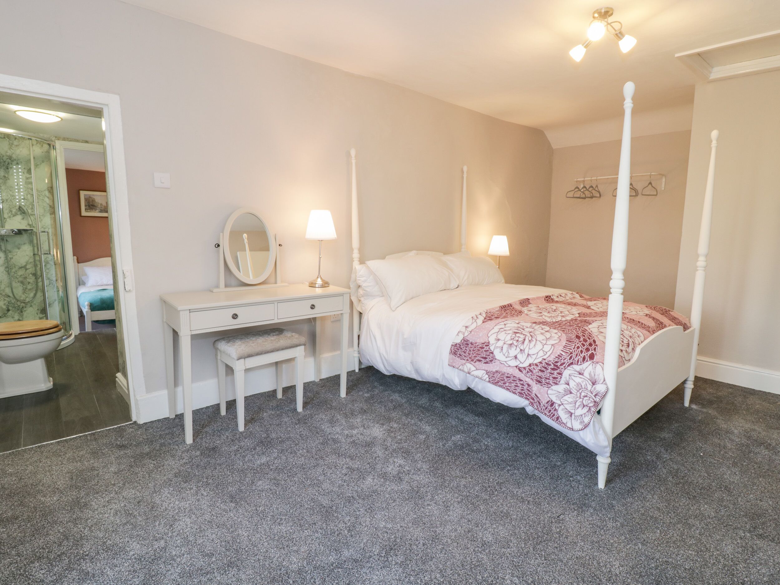 Une chambre à coucher avec un lit à baldaquin, une table de chevet avec une lampe, un miroir et un banc.