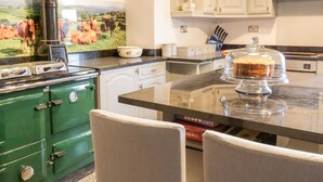 Una cocina con estufa verde, armarios blancos y encimera de mármol.