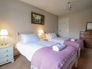 A double room with two beds, bedside tables, lamps, a dresser, and a painting on the wall.