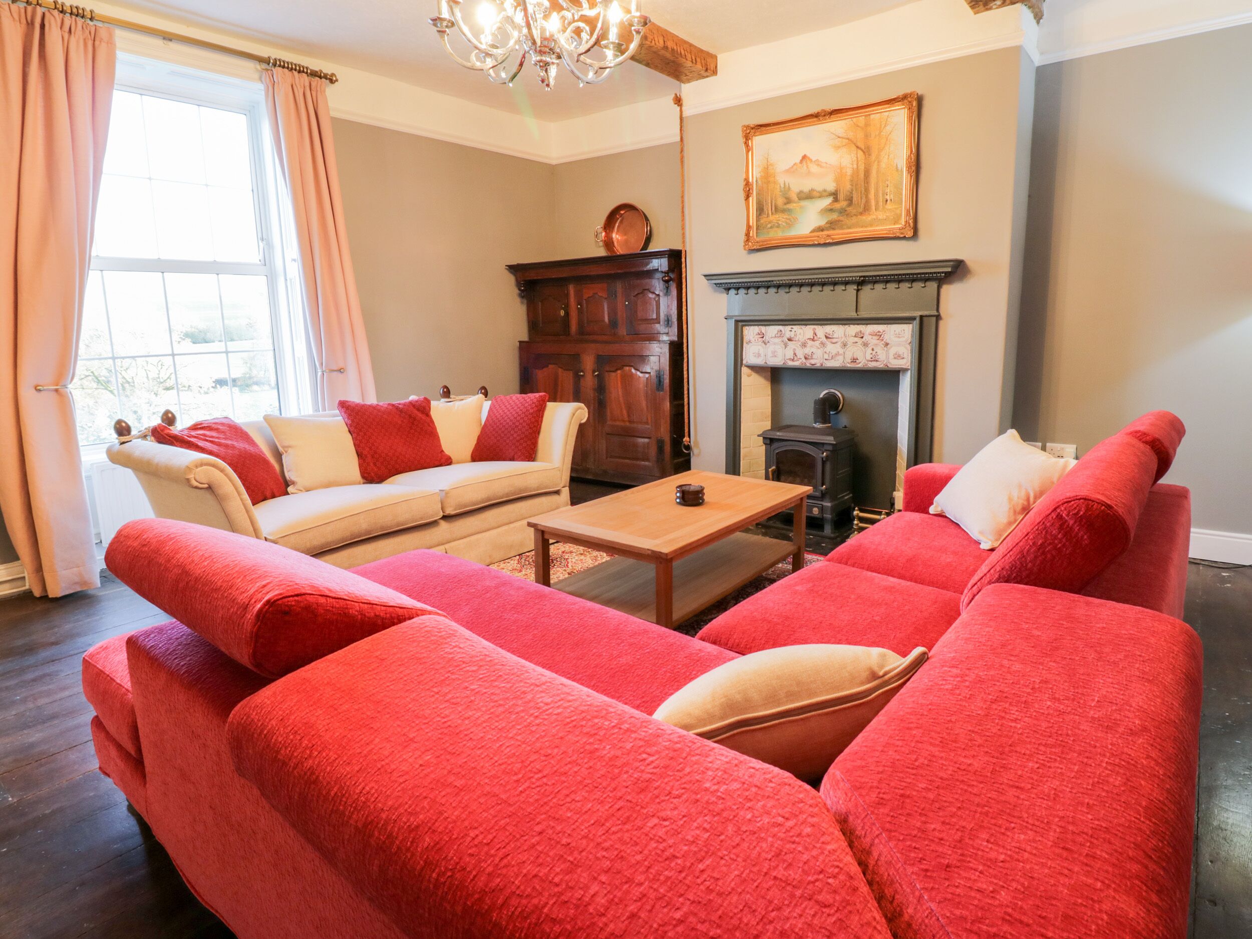 A living room with a beige sofa, red armchairs, a wooden coffee table, and a fireplace.