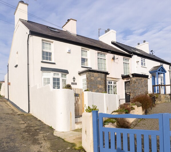 A two-story house with a white exterior, stone accents, and a blue gate. - Old Post Office (Amlwch)