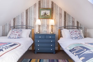 Une chambre avec deux lits, une commode et un tableau au mur.