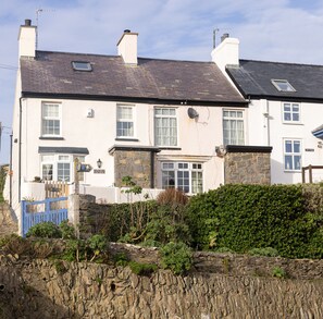 A two-story building with a stone facade, multiple windows, and a small satellite dish. - Old Post Office (Amlwch)