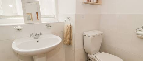 Een badkamer met een witte wastafel, toilet en houten vloer.