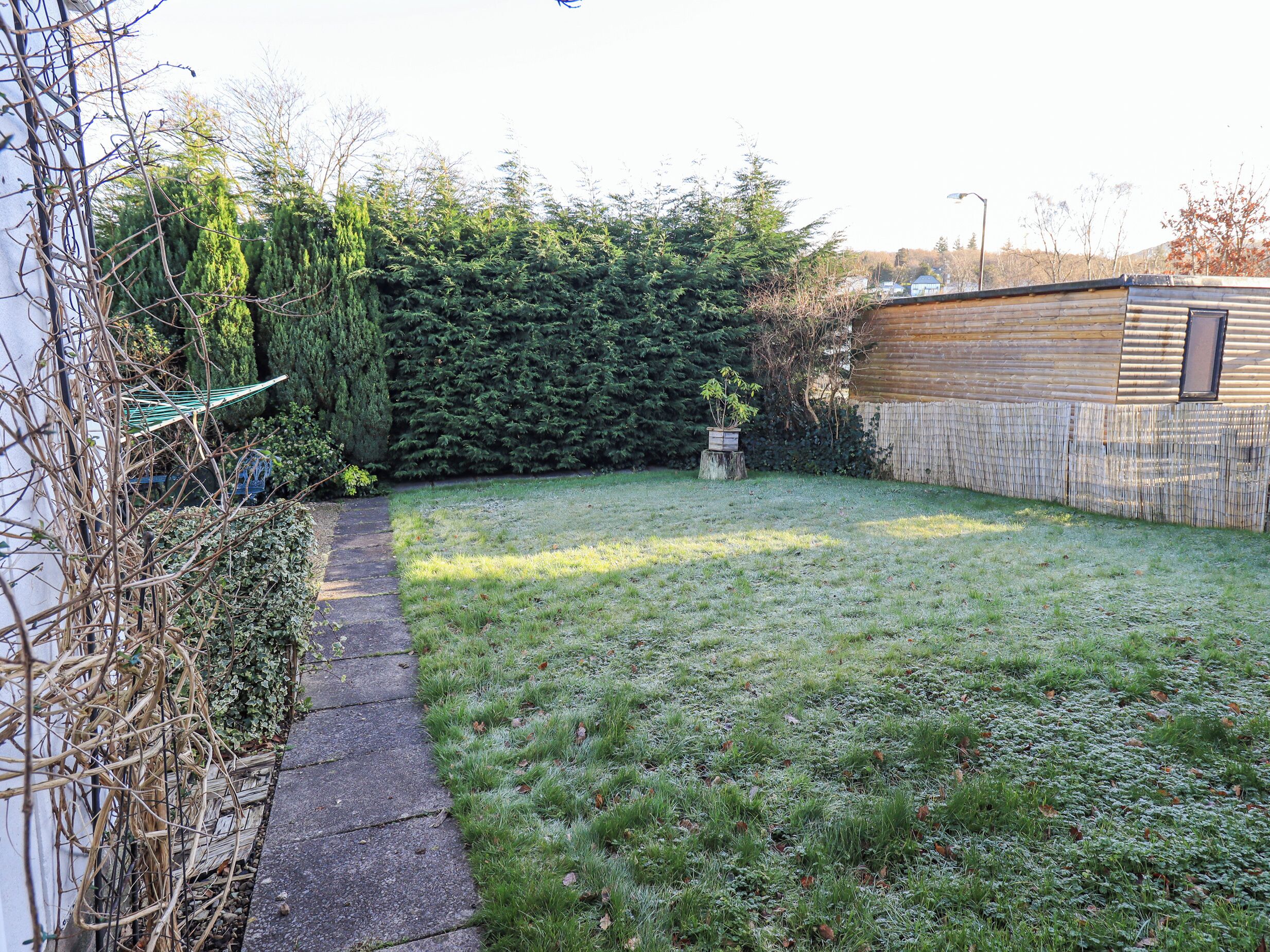 Ein Garten mit Holzzaun, Hecke und kleiner Grünfläche.