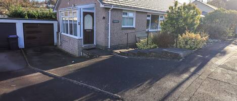 Een tweelaags huis met een garage, een voordeur en een kleine voortuin.