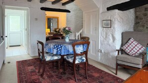 Zona pranzo con tavolo imbandito per quattro persone, tappeto decorato e parete in pietra.