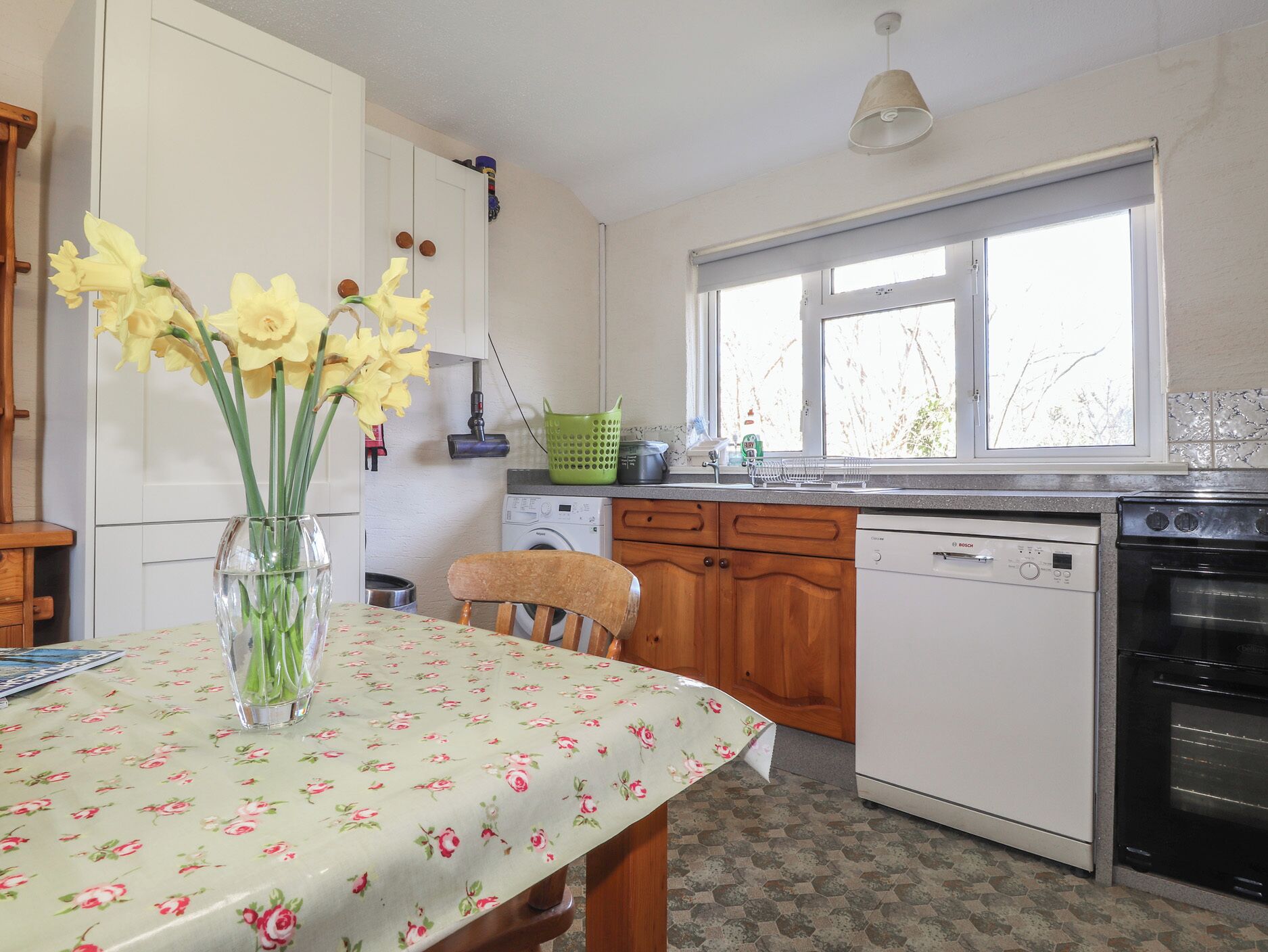 Una cocina con una mesa de comedor, lavadora, lavavajillas y estufa.
