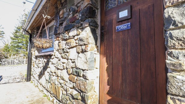 A stone building with a wooden door labeled "Otter". - Otter Cottage (Newport)
