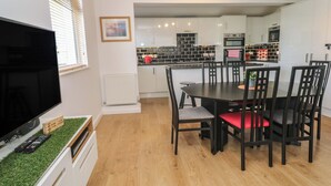 Una cocina moderna con armarios blancos, encimera negra y un comedor con mesa y sillas de madera.