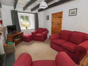 A living room with a television, red sofas, a wooden door, and a window with curtains. - Panteg, Cardigan (Cardigan)