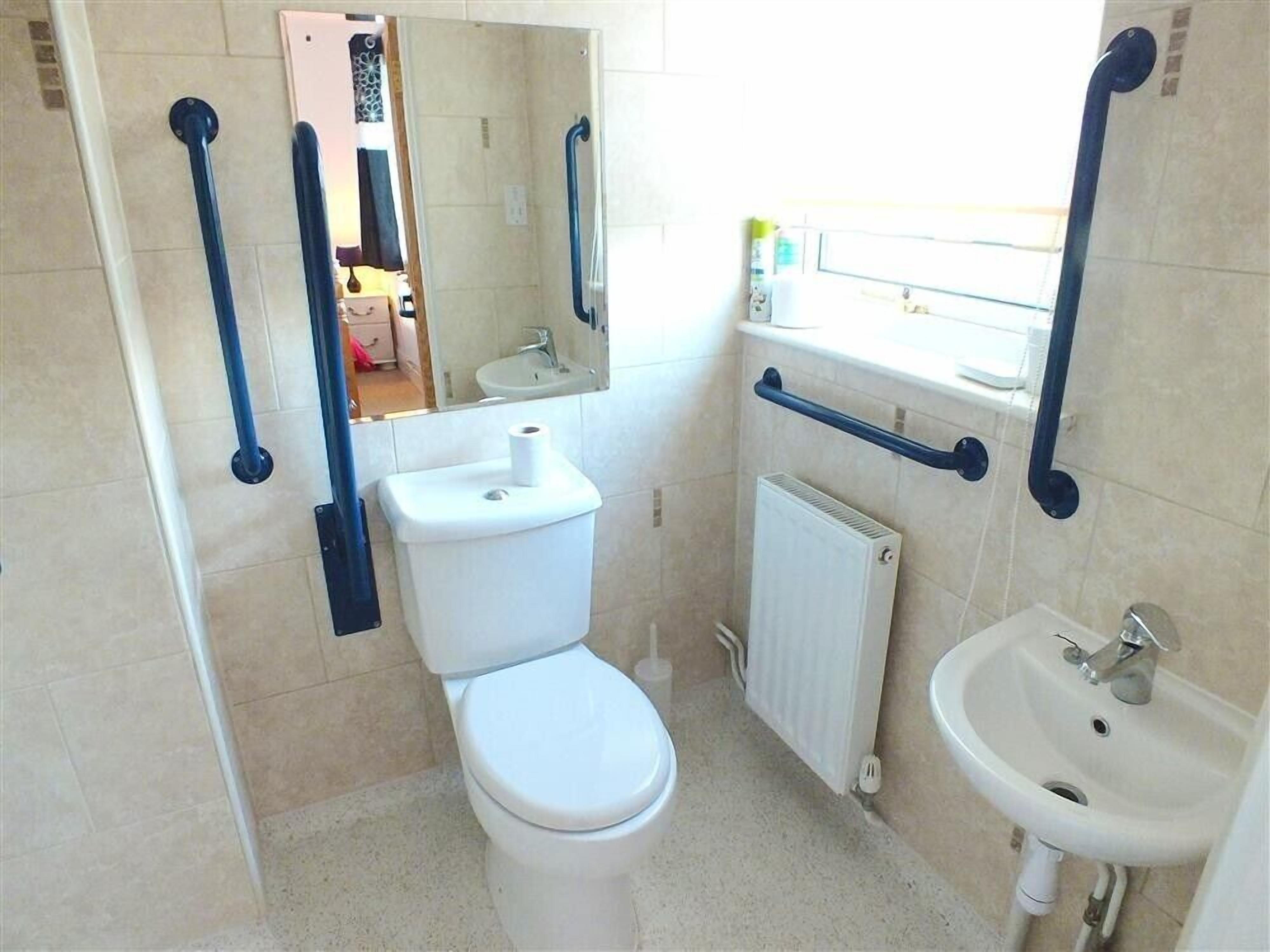A small bathroom with a toilet, sink, and a mirror.