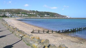 A coastal scene with a paved walkway, a wooden fence, and a calm sea. - Panteurig Farmhouse (Goodwick)