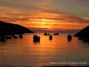 A sunset over a body of water with several boats. - Panteurig Farmhouse (Goodwick)