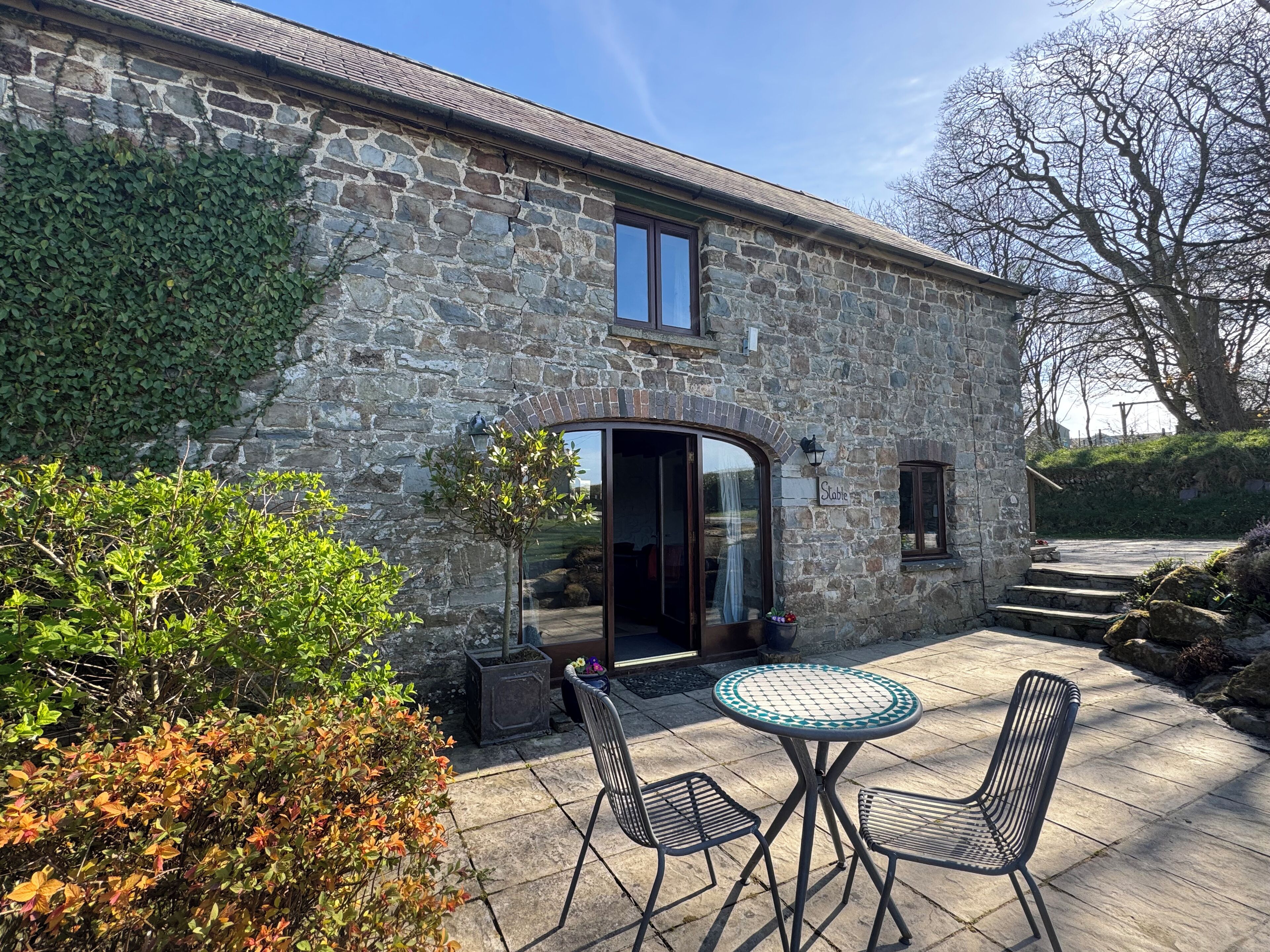 A stone building with a patio area featuring a round table and two chairs.