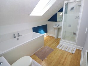 A modern bathroom with a skylight, a bathtub, a sink, and a shower. - Newton West Farm (Haverfordwest)