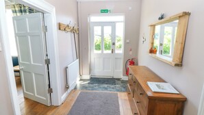 Un pasillo con un aparador de madera, un espejo y una puerta que da a una habitación luminosa.