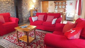 Ein gemütliches Wohnzimmer mit roten Sofas, einem Holztisch und einer Steinwand.