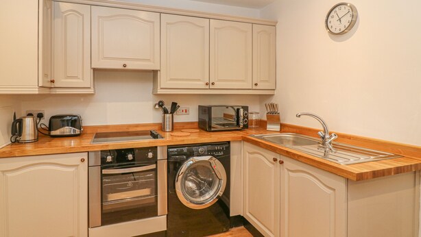 A compact kitchen with a dishwasher, oven, microwave, toaster, and sink. - The Little Bower (Hawes)