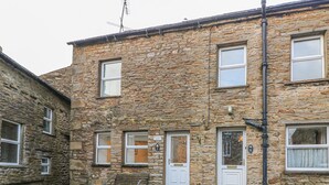 A stone building with multiple windows and doors, a bench outside, and a visible number '1' sign. - The Little Bower (Hawes)