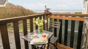 A wooden deck with a table set for tea, overlooking a coastal view. - 5 The Coach House (Haverfordwest)