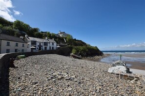 Une plage de galets bordée de bâtiments situés sur une colline, d’où l’on a une vue sur la mer.